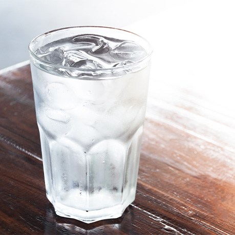 Glass of ice-cold water on table