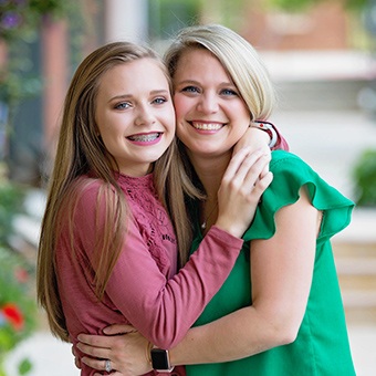 Mother giving teen daughter with braces a hug