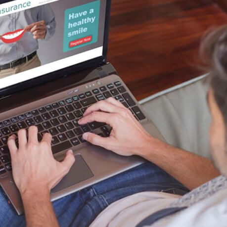 Man looking at dental insurance information on his laptop