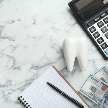 Tooth model, calculator, and money viewed from above