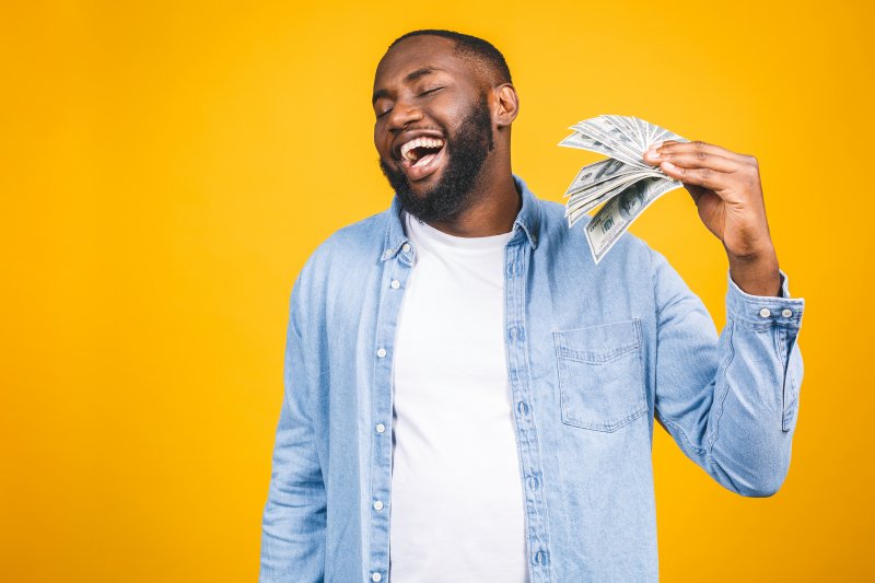 Patient smiling with money for orthodontics
