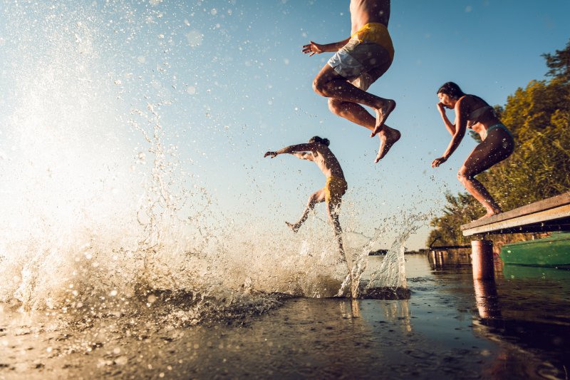 People jump in lake on sunny day